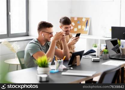 business, people and corporate concept - team of startuppers with gadgets working at office. business team or startuppers working at office