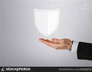 business, people and cyber protection concept - close up of male hand with virtual antivirus program shield icon over gray background. close up of man with virtual antivirus shield icon