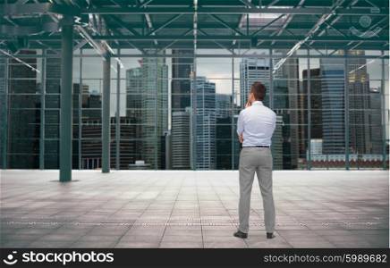 business, people and development concept - businessman thinking over empty urban city construction background from back