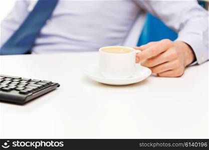 business, people and drinks concept - close up of businessman hand with coffee cup on office table