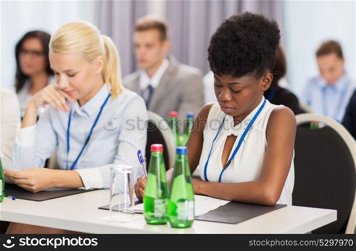 business, people and education concept - african american businesswoman with papers at international conference. businesswoman with files at conference
