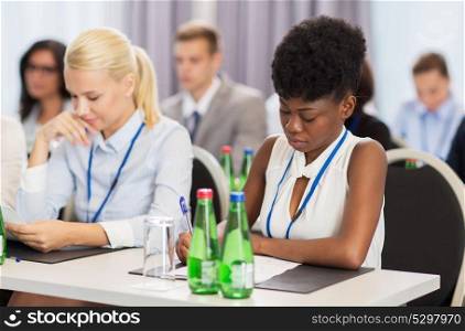 business, people and education concept - african american businesswoman with papers at international conference. businesswoman with files at conference