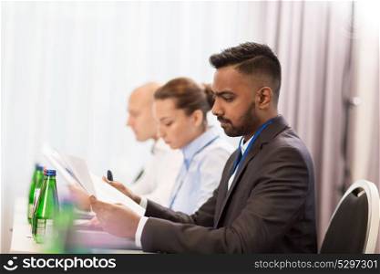 business, people and education concept - businessman with papers at international conference. businessman with files at international conference