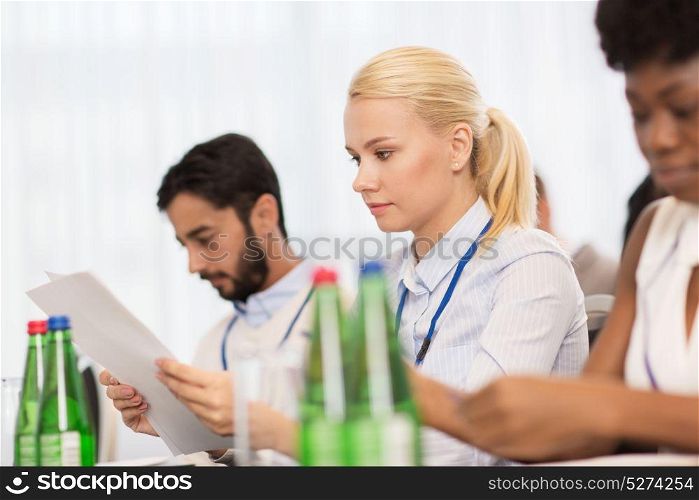 business, people and education concept - businesswoman with papers at international conference. businesswoman with files at conference