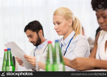 business, people and education concept - businesswoman with papers at international conference. businesswoman with files at conference