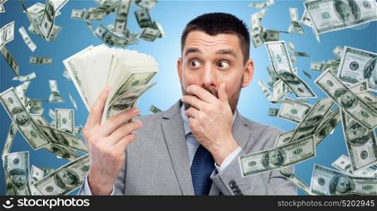 business, people and finances concept - astonished businessman with bundle of american dollar cash money over blue background. smiling businessman with american dollar money