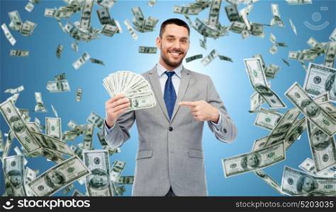 business, people and finances concept - smiling businessman with bundle of american dollar cash money over blue background. smiling businessman with american dollar money