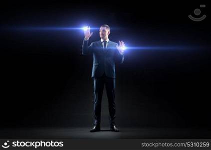 business, people and future technology concept - businessman in suit with laser lights over black background. businessman with laser light over black