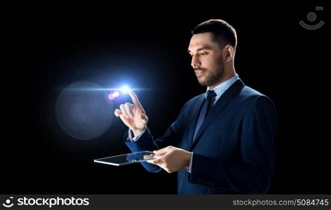business, people and future technology concept - businessman in suit working with transparent tablet pc computer and virtual projection over black background. businessman in suit with transparent tablet pc. businessman in suit with transparent tablet pc