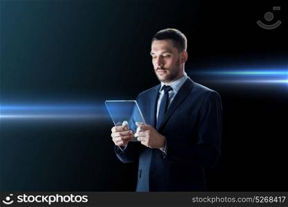 business, people and future technology concept - businessman in suit working with transparent tablet pc computer over black background. businessman working with transparent tablet pc