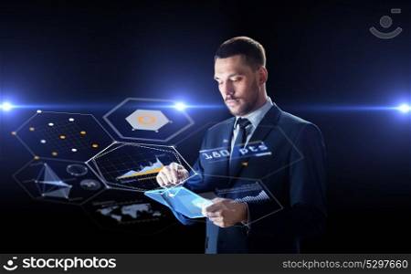 business, people and future technology concept - businessman in suit working with transparent tablet pc computer and charts on virtual screen over black background. businessman with tablet pc and virtual screens