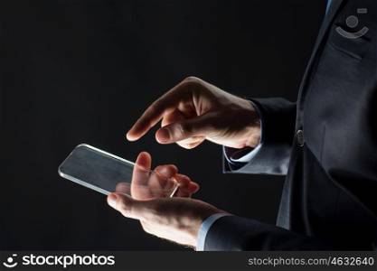 business, people and future technology concept - close up of businessman hands with transparent smartphone over black. close up of businessman with glass smartphone