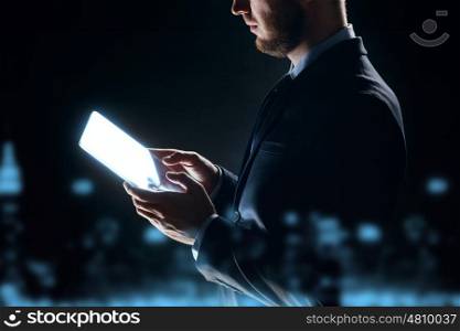 business, people and future technology concept - close up of businessman with transparent tablet pc computer over city lights and dark background