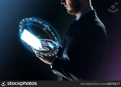 business, people and future technology concept - close up of businessman with transparent tablet pc computer and hologram over dark background