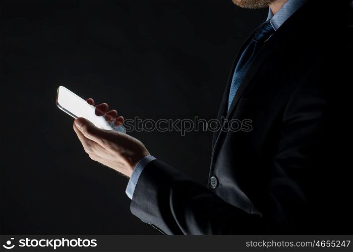 business, people and future technology concept - close up of businessman with transparent smartphone over black