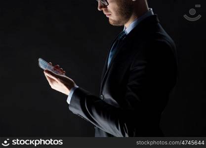 business, people and future technology concept - close up of businessman with transparent smartphone over black