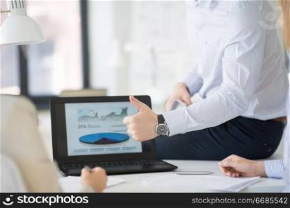 business, people and gesture concept - close up of businessman showing thumbs up at office. businessman showing thumbs up at office