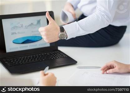 business, people and gesture concept - close up of businessman showing thumbs up at office. businessman showing thumbs up at office