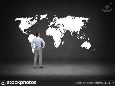 business, people and global communication concept - businessman looking at world map over concrete room background from back