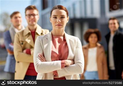 business, people and leadership concept - woman in front of international team on city street. woman in front of international team outdoors