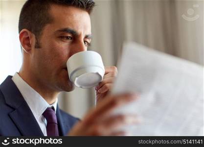 business, people and mass media concept - businessman reading newspaper and drinking coffee. businessman reading newspaper and drinking coffee