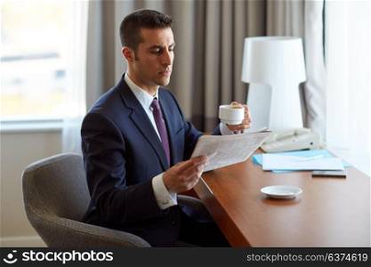 business, people and mass media concept - businessman reading newspaper and drinking coffee at hotel room. businessman reading newspaper and drinking coffee