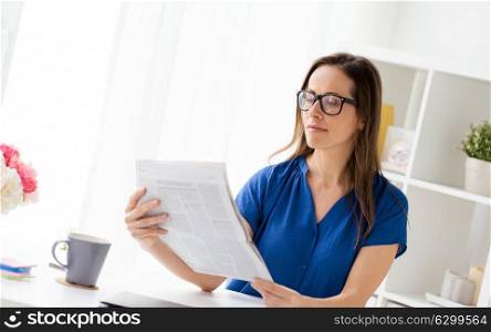 business, people and mass media concept - businesswoman in glasses reading newspaper at office. businesswoman reading newspaper at office