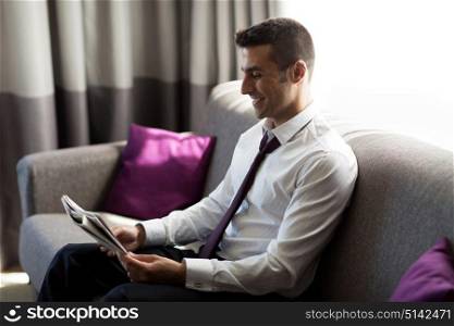 business, people and mass media concept - happy smiling businessman reading newspaper at hotel room. happy businessman reading newspaper at hotel room