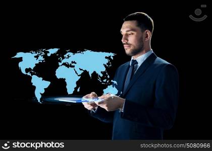 business, people and modern technology concept - businessman in suit with transparent tablet pc computer and world map projection over black background. businessman with tablet pc and world map