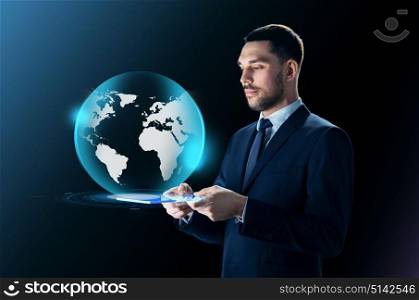 business, people and modern technology concept - businessman in suit working with transparent tablet pc computer and virtual earth projection over black background. businessman with tablet pc and earth projection