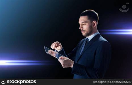 business, people and modern technology concept - businessman in suit working with transparent tablet pc computer over black background and laser light. businessman in suit with transparent tablet pc