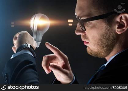 business, people and modern technology concept - close up of businessman with smart watch and lightbulb projection over black background. close up of businessman with smart watch