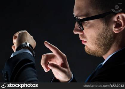 business, people and modern technology concept - close up of businessman with smart watch over black