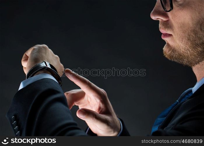 business, people and modern technology concept - close up of businessman with smart watch over black