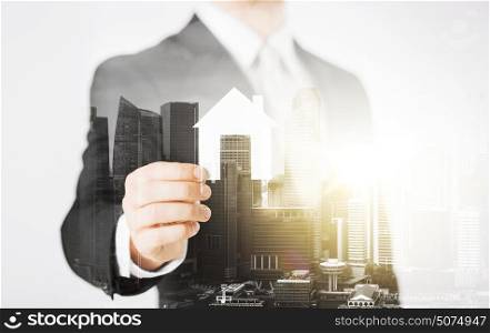 business, people and mortgage concept - close up of businessman holding paper house over city with double exposure. close up of businessman holding paper house