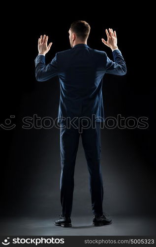 business, people and office concept - businessman in suit touching something invisible over black background. businessman in suit touching something invisible