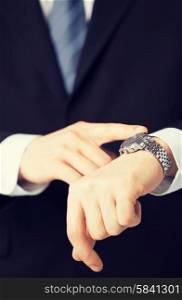 business people and office concept - close up of man looking at wristwatch