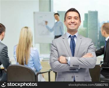business, people and office concept - happy businessman with team at presentation over office room background