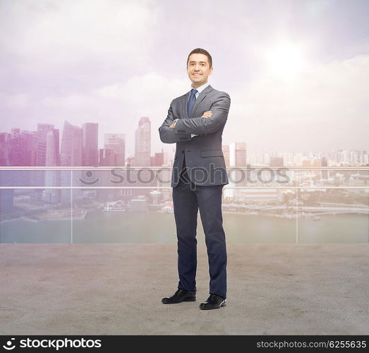 business, people and office concept - happy smiling businessman in dark grey suit over singapore city background