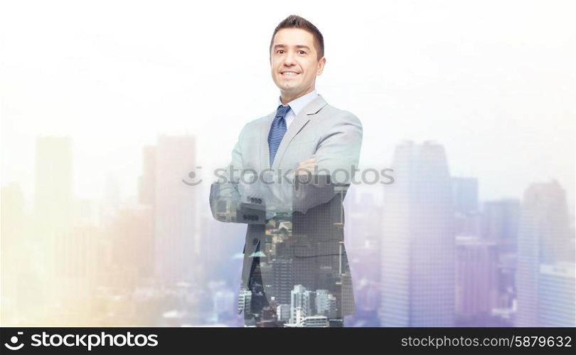 business, people and office concept - happy smiling businessman in suit over city background with double exposure