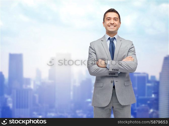 business, people and office concept - happy smiling businessman in suit over city background