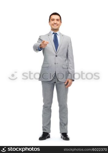 business, people and office concept - happy smiling businessman in suit pointing at you