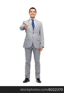 business, people and office concept - happy smiling businessman in suit pointing at you
