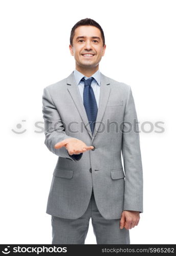 business, people and office concept - happy smiling businessman in suit showing something imaginary on empty palm