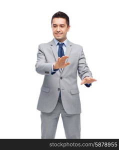 business, people and office concept - happy smiling businessman in suit touching something imaginary