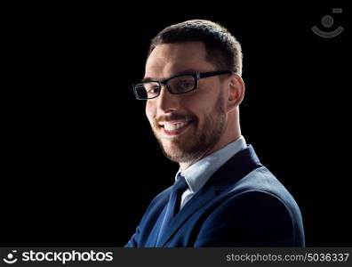 business, people and office concept - smiling businessman in glasses over black background. smiling businessman in glasses over black
