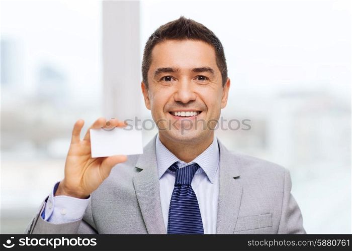 business, people and office concept - smiling businessman in suit showing blank white visiting card