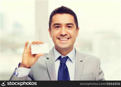 business, people and office concept - smiling businessman in suit showing blank white visiting card
