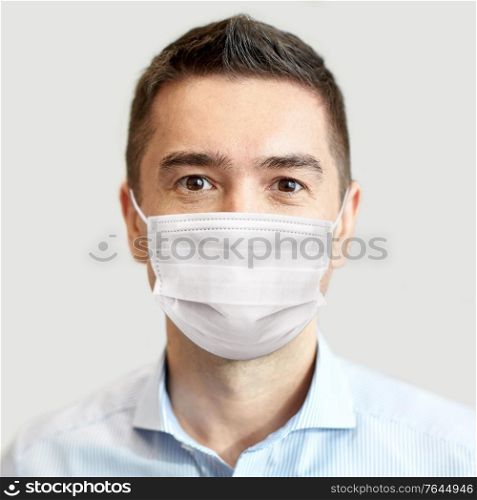 business, people and pandemic concept - businessman wearing face protective medical mask for protection from virus disease over grey background. businessman wearing face protective mask at office