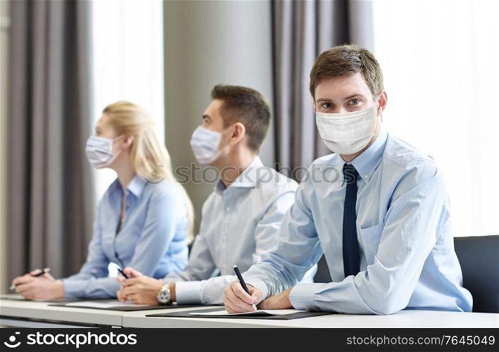 business, people and pandemic concept - businessman wearing face protective medical mask for protection from virus disease at office meeting. group of businesspeople in masks meeting at office